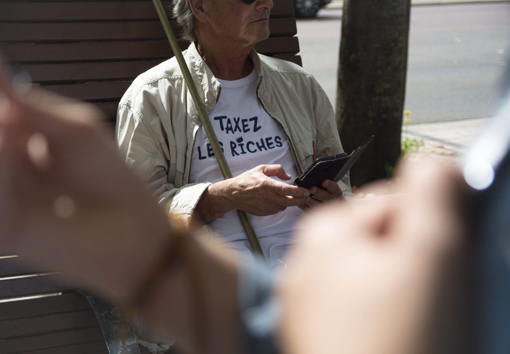 Sous son drapeau LFI, Michel attend le début de la manifestation avec un sourire.